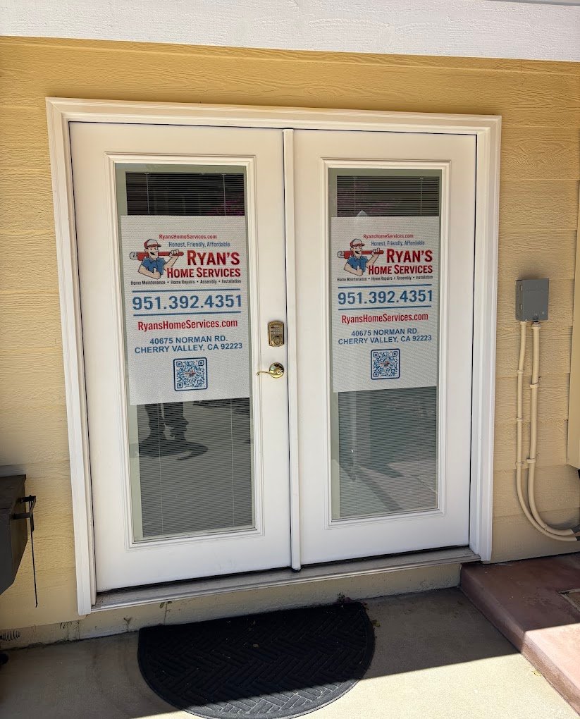 Front glass doors of Ryan's Home Services at 40675 Norman Rd., Cherry Valley, CA 92223, with logo, phone number, and QR code